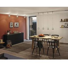 Eetkamer met houten tafel, zwarte stoelen, dressoir en verlichtingssysteem