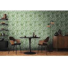 Eetkamer met tafel, stoelen en een rek tegen een groen bladeren behang