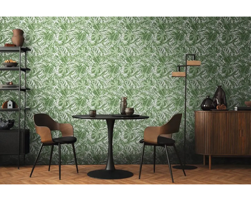 Eetkamer met tafel, stoelen en een rek tegen een groen bladeren behang