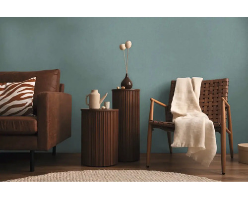 Woonkamer met bruine leren bank, houten tafel, rotan stoel en decoratie