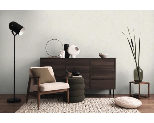 Woonkamer met fauteuil, dressoir, staande lamp en decoratie voor een huiselijke sfeer.