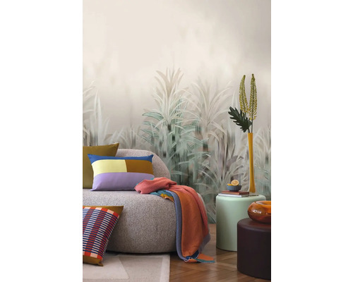 Inrichtingsidee met een bank, kussens, deken en decoratief wandbehang met plantenmotieven.