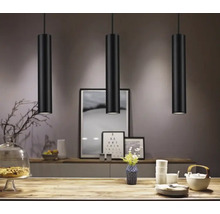 Drie zwarte hanglampen boven een tafel in een eetkamer.