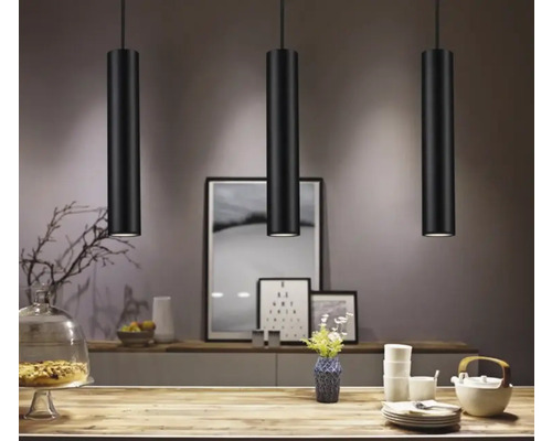 Drie zwarte hanglampen boven een tafel in een eetkamer.