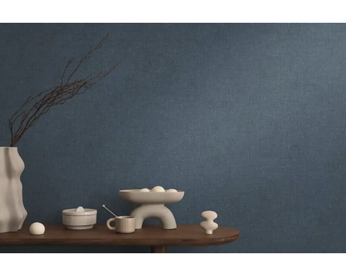 Blauw vliesbehang in woonkamer met decoratie op een houten tafel.