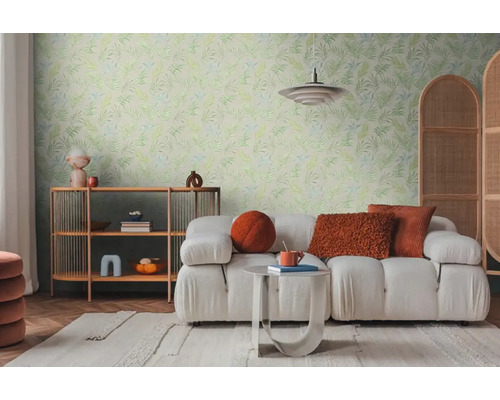 Lichte woonkamer met bank, rek en wandbehang met bladerpatroon