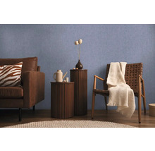 Woonkamerscène met bank, stoel en bijzettafels tegen een blauwe muur