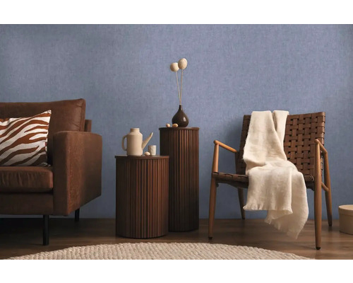 Woonkamerscène met bank, stoel en bijzettafels tegen een blauwe muur