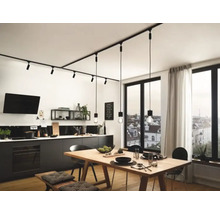 Moderne keuken met lineair railsysteem en hanglampen boven een houten tafel.
