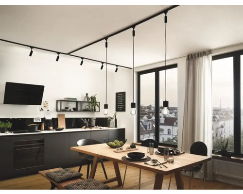 Moderne keuken met lineair railsysteem en hanglampen boven een houten tafel.