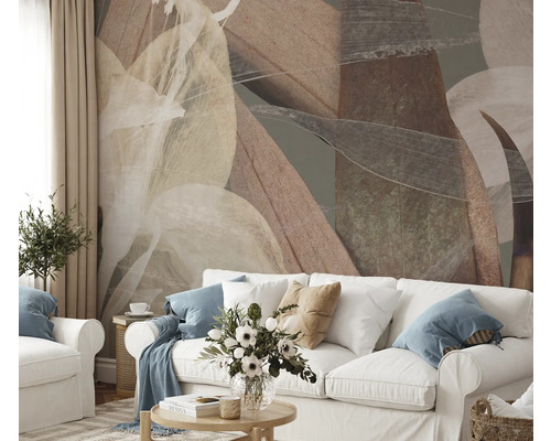 Woonkamer met abstract bladerpatroon op de muur achter een witte bank.