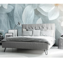 Slaapkamer met bed, nachtkastje en decoratieve bloemenprint op de muur.