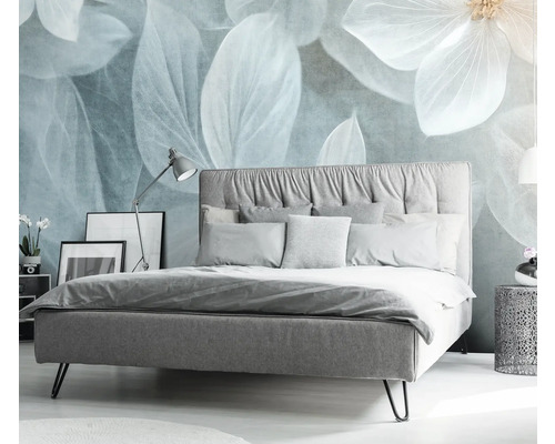 Slaapkamer met bed, nachtkastje en decoratieve bloemenprint op de muur.