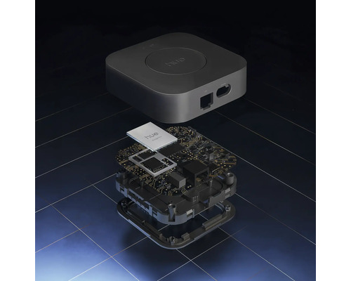Geëxplodeerd overzicht van een Philips Hue Bridge, met de behuizing en de interne printplaat met elektronische componenten.