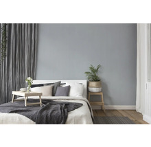 Lichte slaapkamer met bed, kussens, deken, bijzettafel en kamerplant