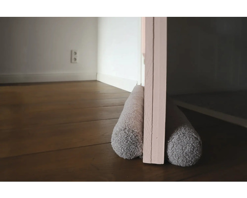 Tochtstopper onder een deur op een houten vloer.