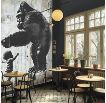 Interieur van een café met een muurschildering van een gorilla en een kind, tafels en stoelen.