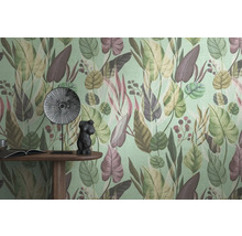 Detailopname van een muur met een behang met bladerpatroon, een tafel met een boek, een decoratief beeldje en een bord.