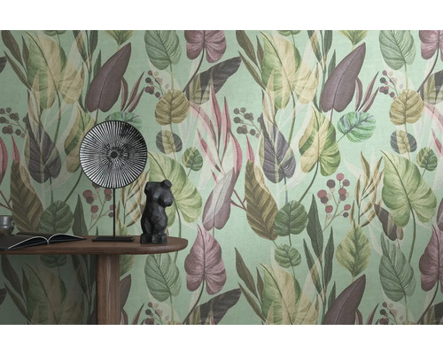 Detailopname van een muur met een behang met bladerpatroon, een tafel met een boek, een decoratief beeldje en een bord.