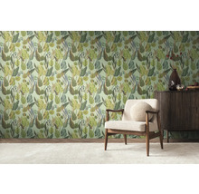 Een kamer met een muur behangen met junglemotieven, een fauteuil en een dressoir.