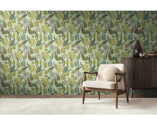 Een kamer met een muur behangen met junglemotieven, een fauteuil en een dressoir.