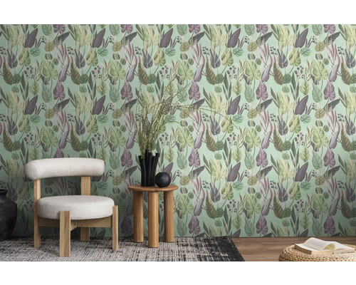 Een kamer met een behang met bladerenmotief, een stoel en een bijzettafel.