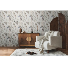 Woonkamer met bloemenbehang, houten dressoir, fauteuil en vloerkleed voor een gezellige sfeer.