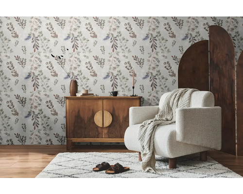 Woonkamer met bloemenbehang, houten dressoir, fauteuil en vloerkleed voor een gezellige sfeer.