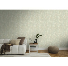 Woonkamer met behang met bladmotief, bank, bijzettafel en poef