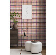 Woonkamerinterieur met geruite wandbekleding, ladekast, kruk en decoraties voor een gezellige sfeer.