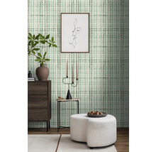 Woonkamer met patroonbehang, ladekast, bijzettafel en hocker.