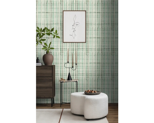 Woonkamer met patroonbehang, ladekast, bijzettafel en hocker.