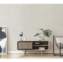 Woonkamer met dressoir, decoraties, plant en fauteuil.