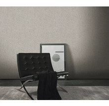 Woonkamer met een grijs structuurbehang, een zwarte fauteuil en een ingelijste afbeelding