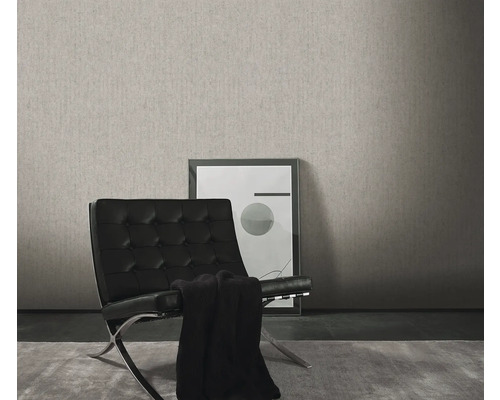 Woonkamer met een grijs structuurbehang, een zwarte fauteuil en een ingelijste afbeelding