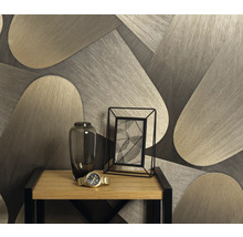 Decoratief behang met geometrisch patroon achter een tafel met bloemenvaas, fotolijst en polshorloge