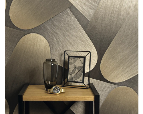 Decoratief behang met geometrisch patroon achter een tafel met bloemenvaas, fotolijst en polshorloge