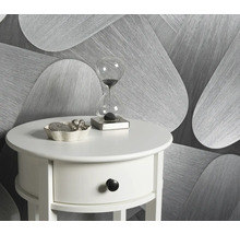 Scene met een witte bijzettafel, een zandloper en een decoratieve schaal tegen een achtergrond van behang met motief