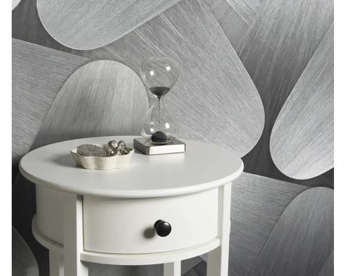 Scene met een witte bijzettafel, een zandloper en een decoratieve schaal tegen een achtergrond van behang met motief