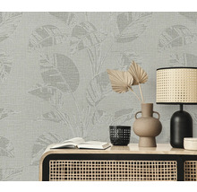 Scene met een wandbekleding met plantenpatroon, een tafel, een lamp, een vaas en een boek.