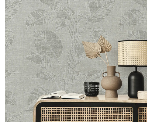 Scene met een wandbekleding met plantenpatroon, een tafel, een lamp, een vaas en een boek.