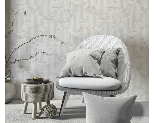 Decoratieve scène met stoel, kussens en behang met patroon voor een heldere en georganiseerde ruimtesfeer.