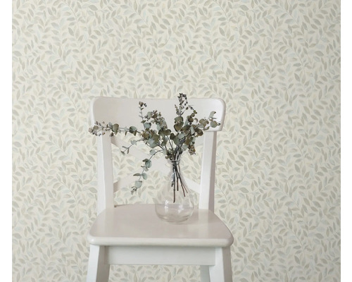 Decoratief behang met bladerpatroon, gecombineerd met een stoel en een vaas met takken voor een stijlvolle kamerambiance.