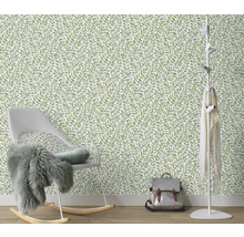 Kamer met een behang met bladmotief, een schommelstoel en een kapstok.