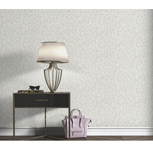 Woonkamerscène met een wandbehang met bladmotief, een nachtkastje, een lamp en een handtas.