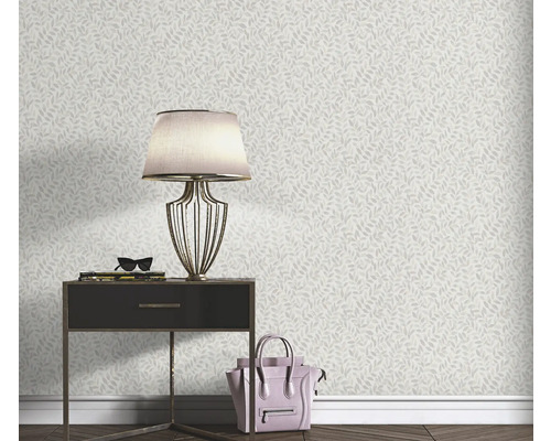 Woonkamerscène met een wandbehang met bladmotief, een nachtkastje, een lamp en een handtas.