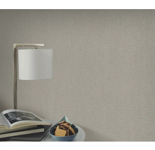 Close-up van een gestructureerd behang in een woonkamer met lamp en decoratie.