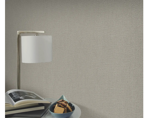 Close-up van een gestructureerd behang in een woonkamer met lamp en decoratie.