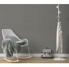 Woonkamer met schommelstoel, kapstok en rugzak tegen een grijze muur