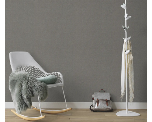 Woonkamer met schommelstoel, kapstok en rugzak tegen een grijze muur